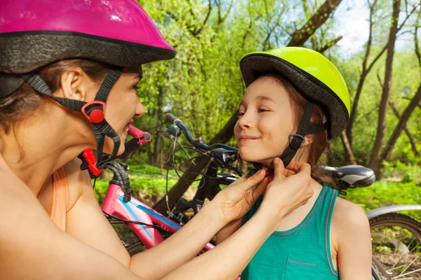 Madre sujetando el casco de su hija — Foto de Stock