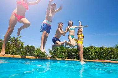 Birçok mutlu küçük çocuk şişme oyuncaklarla suya dalıyor flamingo çörekleriyle yüzme havuzuna atlıyor.