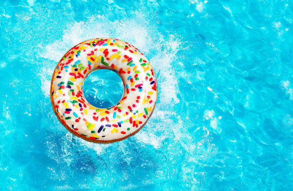 Inflatable candy doughnut buoy splash into the swimming pool view from above