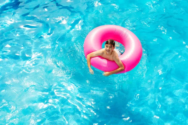 从上面看快乐的小男孩骑着充气粉红环浮标游泳 — 图库照片