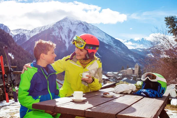 妈妈和一个穿着滑雪服的小男孩聊天 滑雪后在山上享受午休 — 图库照片