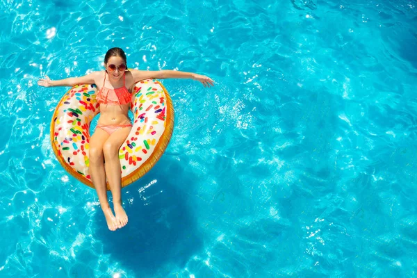 ビュー上からの巻きティーン女の子でサングラスジャンプで水に泳ぎますオンインフレータブルリングドーナツ — ストック写真