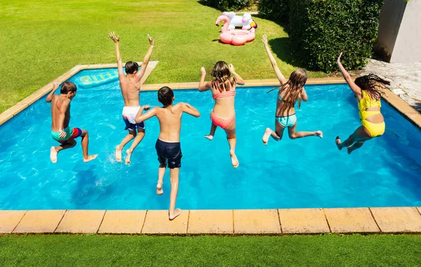 Many cute children jump into the swimming pool about to dive view from above