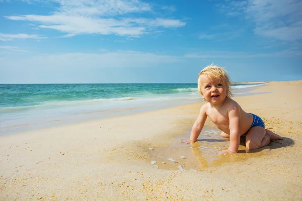 Szczęśliwy Uśmiechnięty Maluch Czołga Się Piasku Pobliżu Plaży Morskiej Patrząc — Zdjęcie stockowe