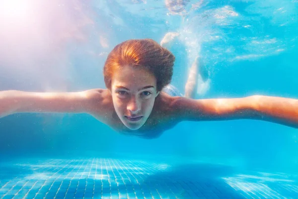 自信を持って顔の表情でプールの中で水中で泳ぐ男の子のアクティブな動きの肖像画 — ストック写真
