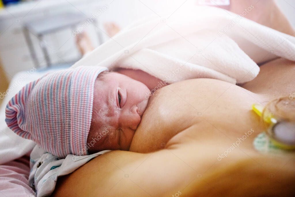 Close photo of mother breastfeeding newborn baby after labor in hospital