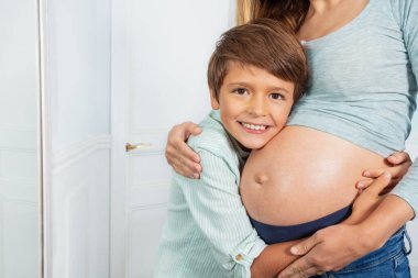 Mutlu evlat, annenin hamile karnına sarıl. Kocaman bir gülümsemeyle.