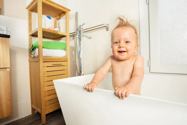 一个金发碧眼的小男孩站在浴室浴缸里微笑的画像 — 图库照片