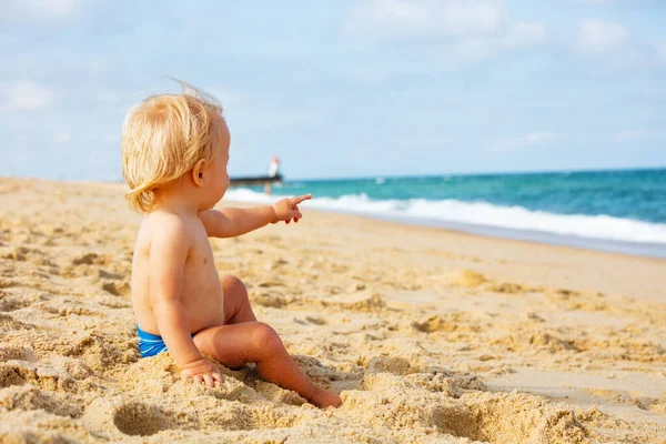 Portret Małego Spokojnego Blondyneczka Siedzącego Wskazującego Morze Plaży Pobliżu Latarni — Zdjęcie stockowe