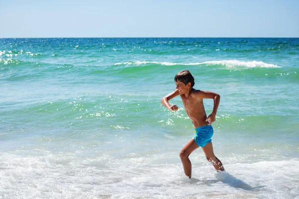 Glücklicher Junge Läuft Rande Des Strandes Mit Meereswellen Hintergrund — Stockfoto