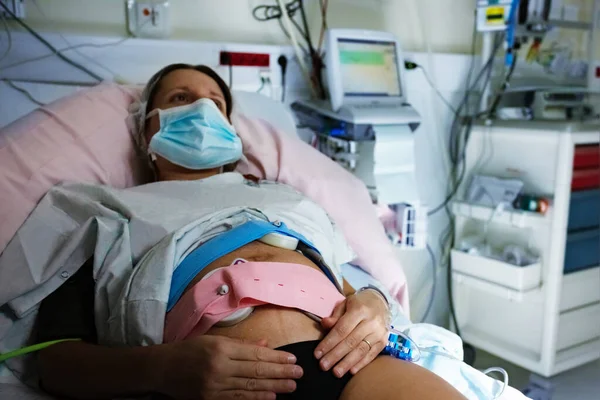Photo of pregnant woman in labor in hospital with monitor on background