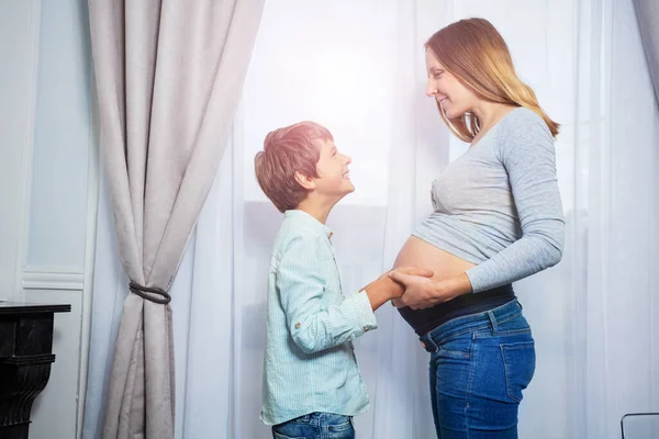 怀孕妇女 男婴手牵手摸着窗户附近的肚子 — 图库照片