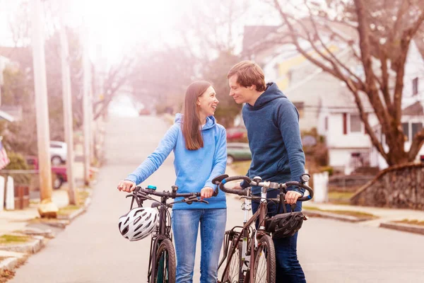 Young couple walk and closely talk holding bikes on the street in USA