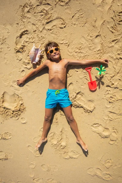 Αγόρι Ξαπλωμένο Στην Άμμο Κέλυφος Και Πλαστική Σέσουλα Φορώντας Αποχρώσεις — Φωτογραφία Αρχείου