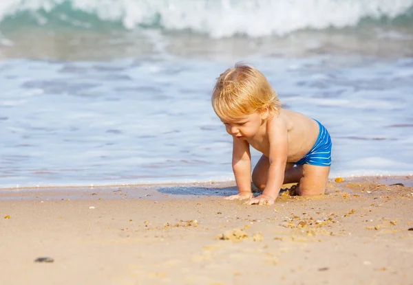 Liten Blond Liten Pojke Krypa Sandstranden Nära Havet Vågor — Stockfoto