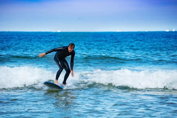 男はサーフボードでサーフィンを学ぶ小さな波の上にボードの上に立つために慣れる — ストック写真