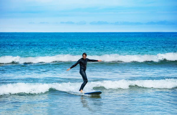 ボード上に立つことを学ぶ小さな波の中でサーフボードに乗る男の肖像画 — ストック写真
