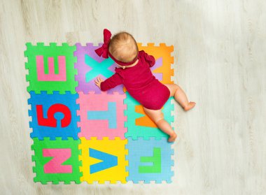 View from above of a little baby girl crawl on the color abc carpet with letters and numbers