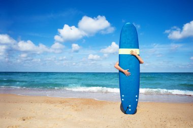 Man surfer hold surf board hugging with hands standing near sea waves on background
