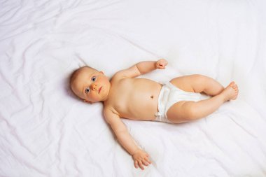 Little baby boy lay on the white in bed sheet view from top