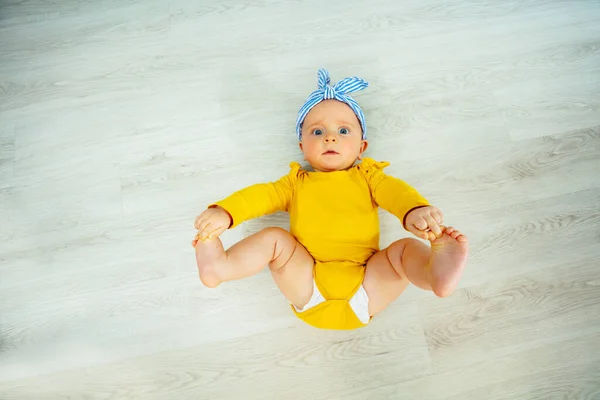 美しい小さな赤ちゃんの女の子が床に横になって弓を着用し 上からの眺めを見上げます — ストック写真