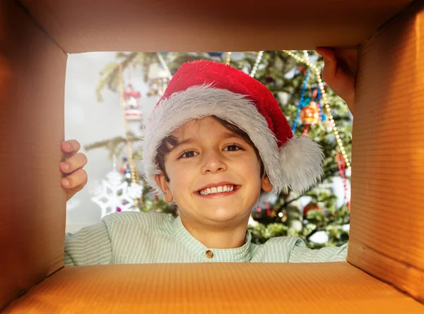 Child Looks Present Box Wearing Santa Hat Christmas Tree Background — Foto Stock