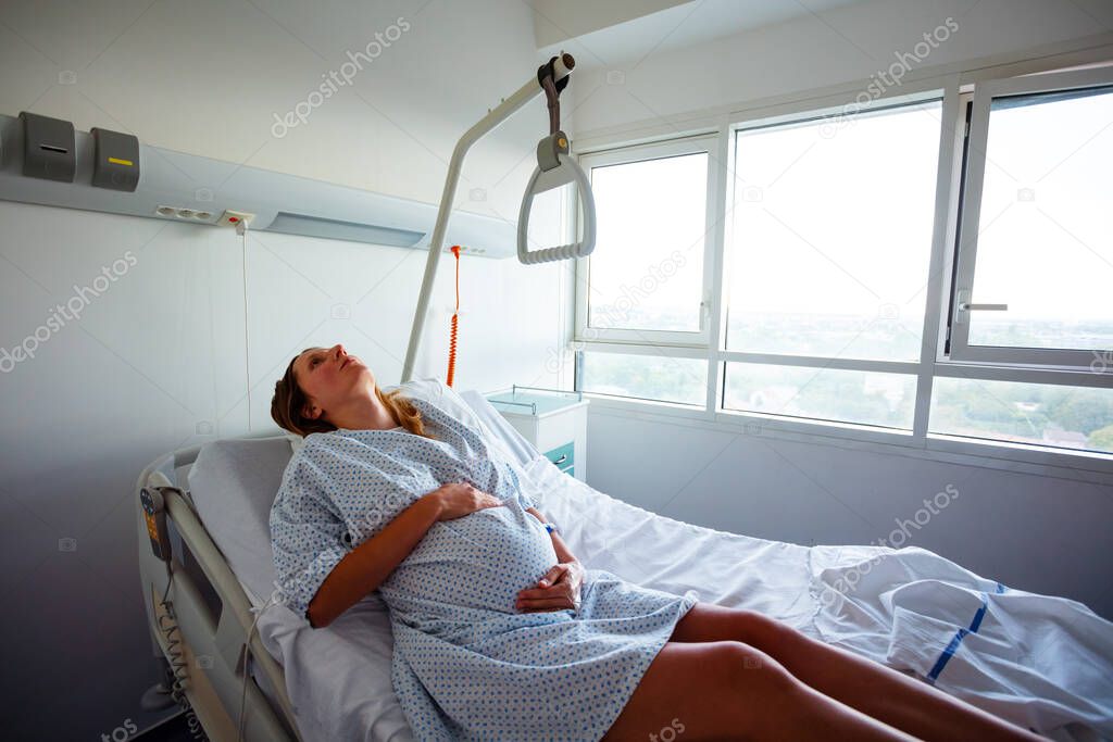 Woman in hospital bed in pain during labor in maternity ward view from above