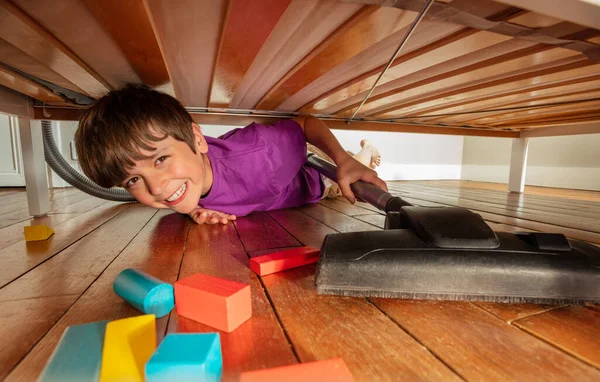 男の子取得下ベッド真空きれいな床で彼の部屋に多くの色のブロック — ストック写真