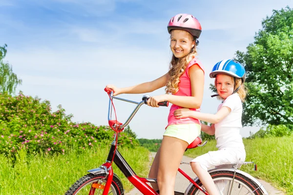 Two little girls sitting on bicycle — Stock Photo, Image