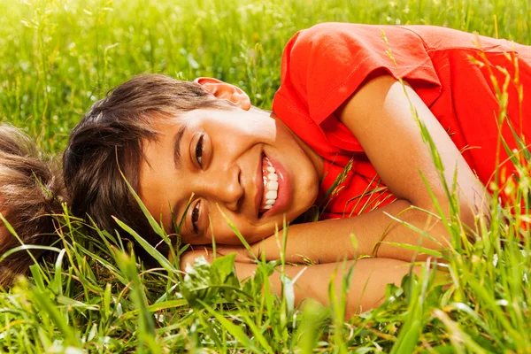 Feliz sorrindo menino deitado na grama — Fotografia de Stock