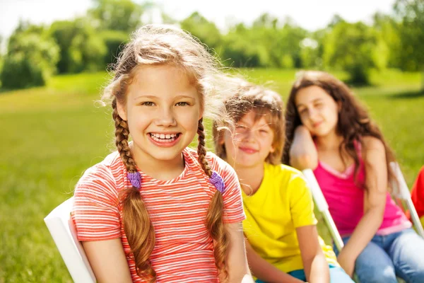 Glückliches Mädchen mit Zöpfen und Freunden — Stockfoto