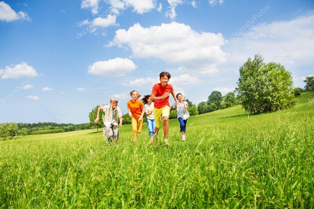Fotos de Niños divertidos corriendo juntos en el campo Imagen de