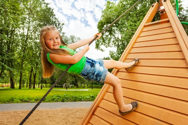 Cute girl climbs on wooden construction — Stock Photo, Image