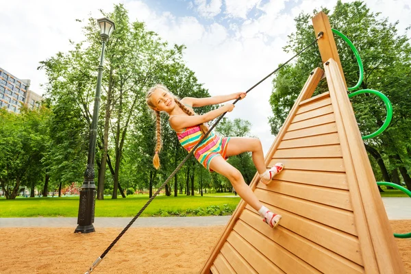 Девушка лазает по деревянной конструкции — стоковое фото