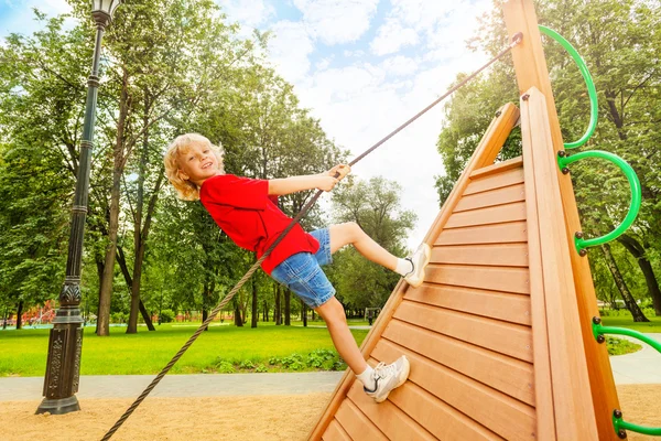 Boy climbs on wooden construction — Stock Photo, Image
