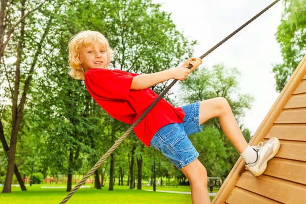 Boy climbs on wooden construction — Stock Photo, Image