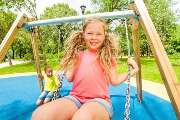 Girl swinging and boy behind — Stock Photo, Image