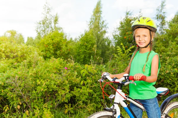 Glad flicka i hjälm innehar cykel — Stockfoto