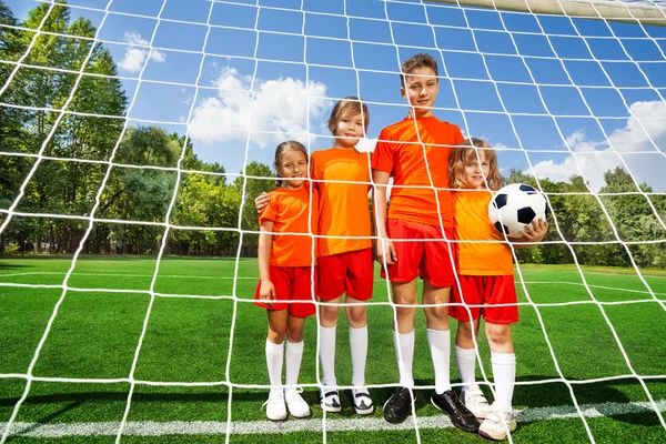 Дети разного роста стоят с футболом — стоковое фото
