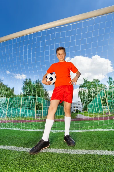 Menino com bola fica perto de madeira — Fotografia de Stock