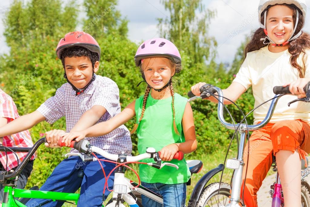 Three kids in helmets on bikes