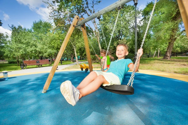 Boy and girl on swings — Stock Photo, Image