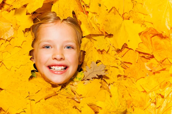 Küçük gülümseyen yüzünü sarışın kız akçaağaç yaprakları — Stok fotoğraf
