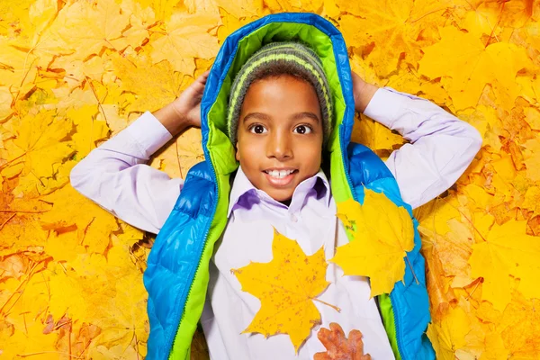 Ragazzo sorridente che posa in foglie — Foto Stock