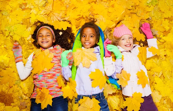 Menino e meninas nas folhas de outono — Fotografia de Stock