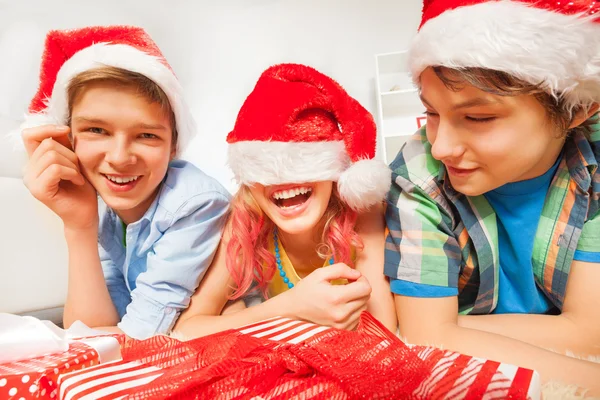 Děti v Santa klobouky leží na podlaze — Stock fotografie