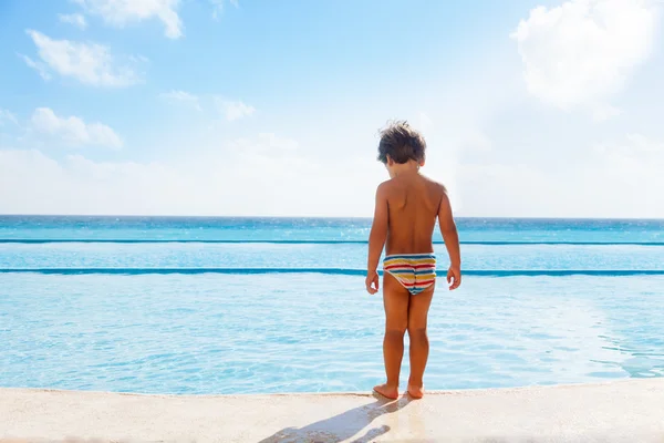 Chłopiec na kamień graniczny z basenem — Zdjęcie stockowe