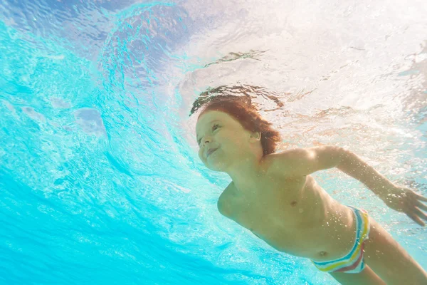 Мальчик плавает под водой бассейна — стоковое фото
