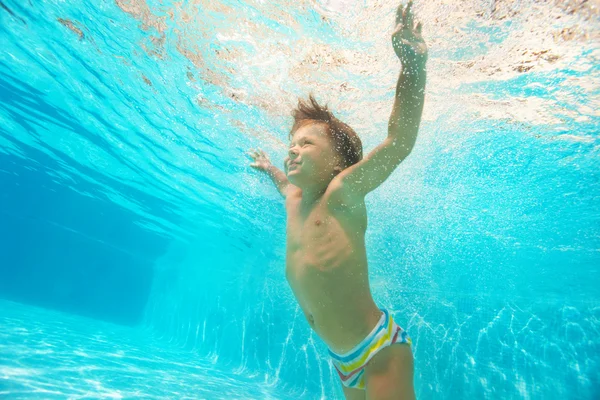 Мальчик плавает под водой бассейна — стоковое фото