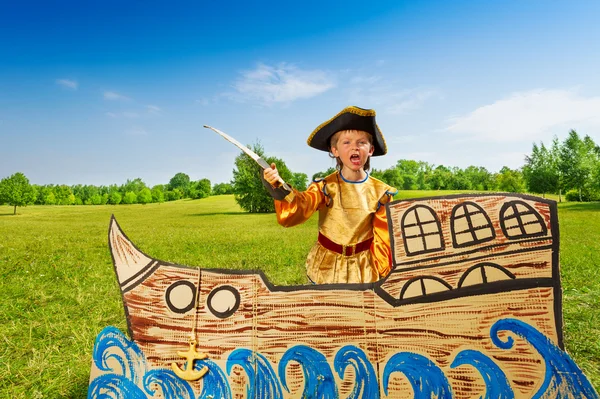 Pojke står på fartyg med svärd — Stockfoto